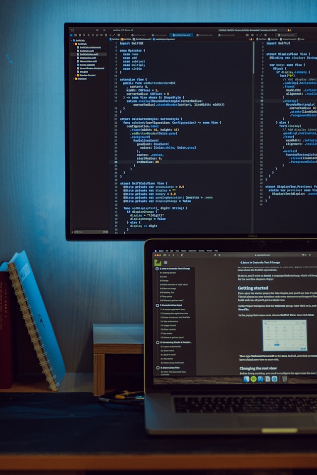 A laptop with a monitor above it, both displaying code