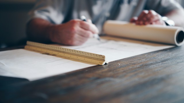 Someone drawing up a plan with a ruler and papers